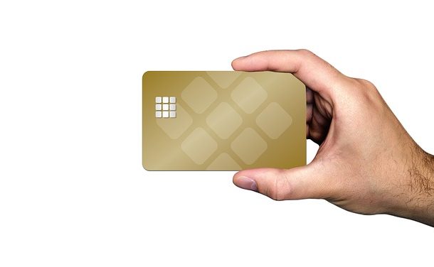 Mężczyzna trzyma w dłoni zlotą kartę kredytową