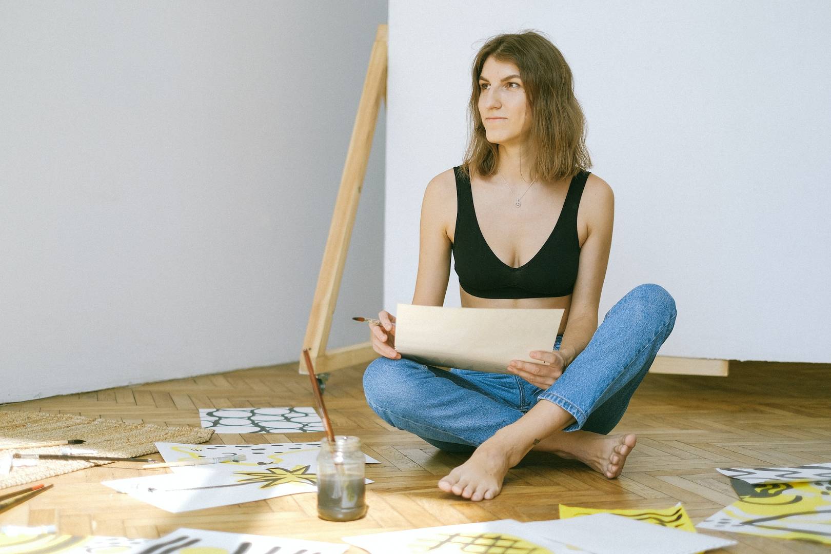 Kobieta siedzi na podłodze i maluje obrazy