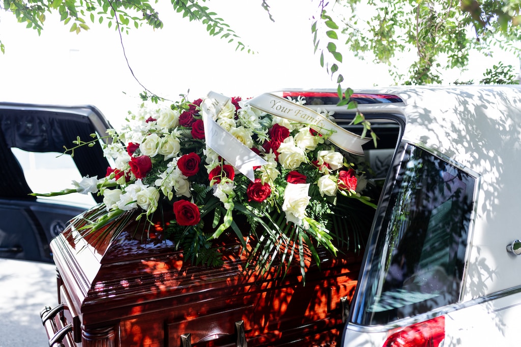 Odpowiednio dobrane kwiaty na pogrzebie leżą na trumnie
