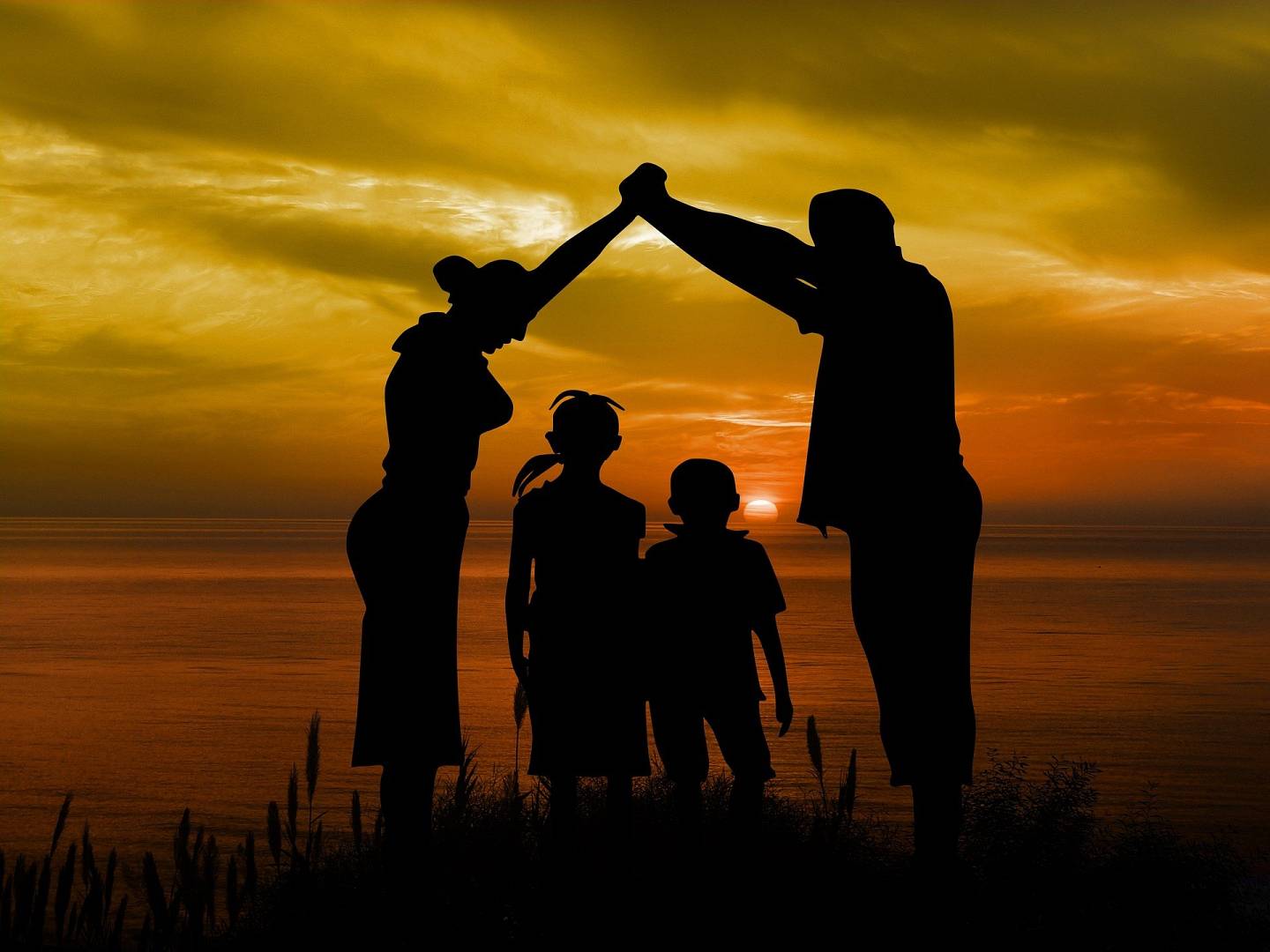 Pełna rodzina, czyli rodzie i dwójka dzieci stoją razem przy zachodzie słońca
