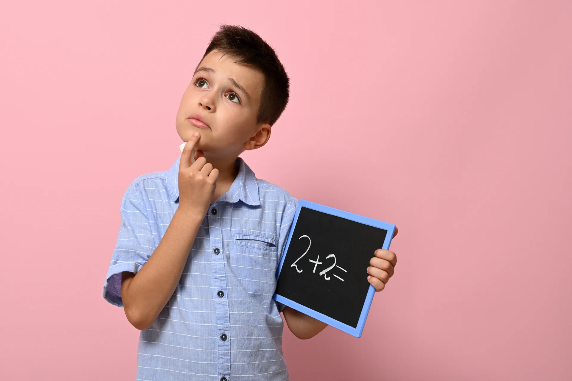 Chłopiec z tabliczką rozwiązuje zadanie matematyczne